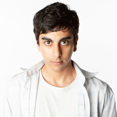 Obraz premium Teenagers: Confidence. A strong direct look from a late teenage boy of Indian heritage isolated against a neutral background. From a series of related images.