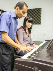 Music Students: Piano Lesson. A late teenage girl listening carefully to the instruction of her...