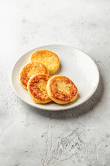 Cottage cheese pancakes on a plate on light background isolated. Homemade dessert syrniki for healthy breakfast, text space
