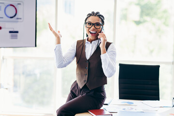 Energetic businesswoman talking on the phone in a bright modern office, exuding confidence and...