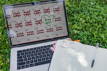 Laptop placed in grass displays clean calendar layout with crossed red 'HARD WORK' days and one...