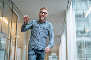 Man waves in modern office corridor. Friendly greeting. Use for business, design, web.