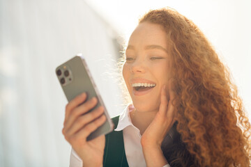 Confident young businesswoman enjoying leisure outdoors with smartphone during a sunny day in the...