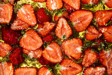 Halves of fresh ripe strawberries in water, summer juicy fruit berry background.