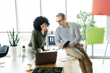 Business professionals collaborate on a project in a modern office setting, fostering teamwork,...