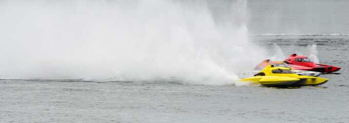Panorama motion blur of three racing speedboats in formation, leaving high spray patterns behind them