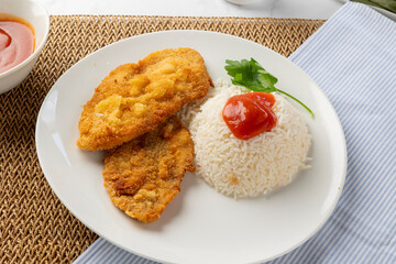 Breaded milanesa with rice, tomato sauce and parsley on white plate