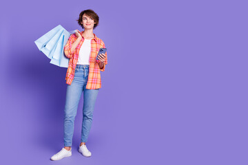 Full body portrait of pretty young lady hold smart phone bags wear shirt isolated on purple color...