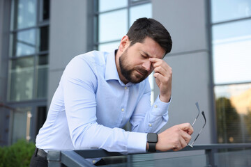 Tired businessman with glasses outside office building