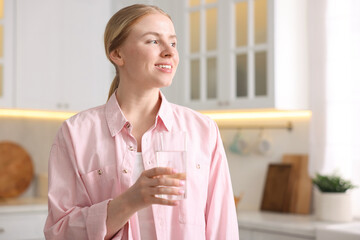 Young woman with glass of water in kitchen