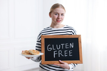 Woman holding small chalkboard with text Gluten Free and pretzels indoors