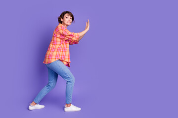 Full length profile portrait of nice young lady push empty space wear shirt isolated on purple...