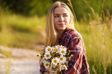 Beautiful woman with bouquet of wildflowers in meadow