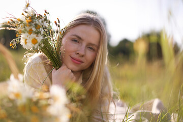 Beautiful woman with wildflowers in meadow on sunny day