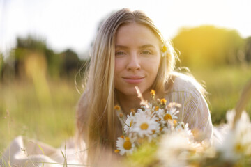 Beautiful woman with wildflowers in meadow on sunny day