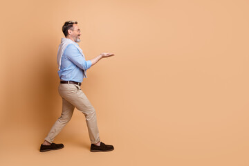 Mature male in stylish casual wear making a hand gesture against a beige background, showcasing...