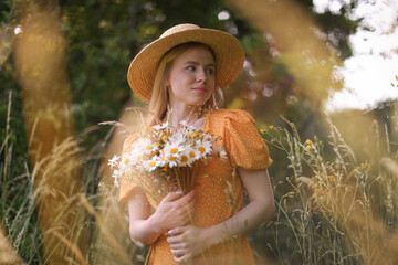 Beautiful woman with bouquet of wildflowers in meadow
