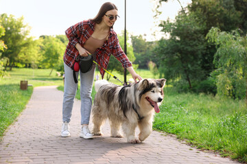 Happy woman walking with her cute Alaskan malamute dog in park