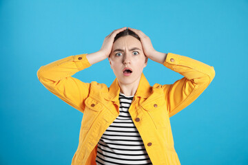 Portrait of shocked woman on light blue background