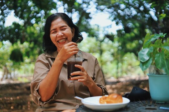 middle-aged woman enjoying coffee and pastry outdoors