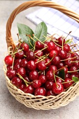 Wet ripe cherries in basket on light table, closeup