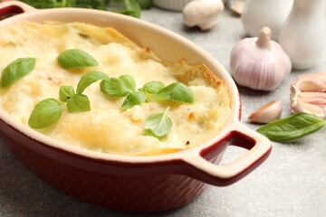 Tasty vegetarian lasagna and ingredients on grey table, closeup