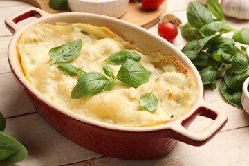 Tasty vegetarian lasagna and ingredients on wooden table, closeup