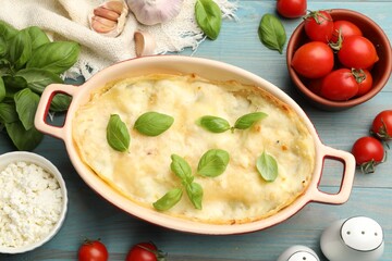 Tasty vegetarian lasagna and ingredients on light blue wooden table, flat lay