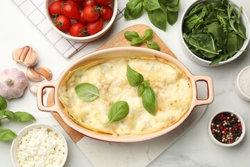Tasty vegetarian lasagna and ingredients on white marble table, flat lay