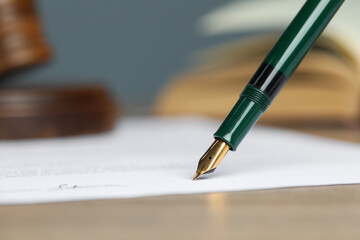 Signing notary document with fountain pen at table, selective focus. Space for text