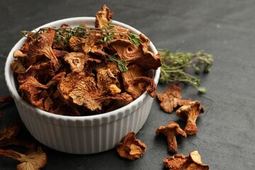 Dried chanterelle mushrooms with thyme on black table, closeup