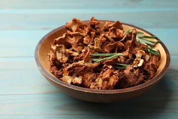 Dried chanterelle mushrooms with rosemary on blue wooden table, closeup