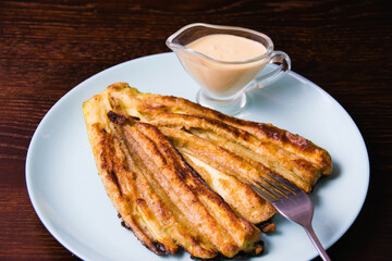 Delicious fried zucchini with aromatic sour cream garlic sauce on a plate on dark table