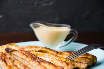 Delicious fried zucchini with aromatic sour cream garlic sauce on a plate on dark table