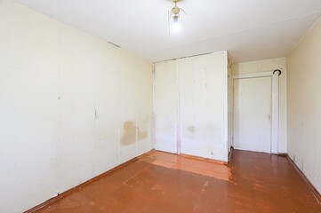 Empty room with aged wallpaper, painted wood floors, & old light fixture. The room has a built-in...