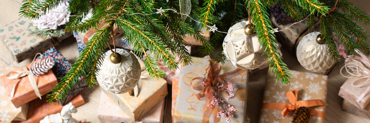 Rustic-themed Christmas gift boxes in natural tones resting beneath a Christmas tree, surrounded by...