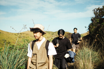 Three male hikers on a grassy trail in East Java, Indonesia