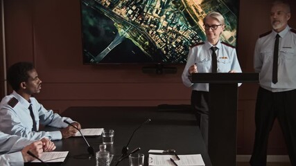 Pan wide shot of two Caucasian strategic consultants briefing navigation map while having military conference with diverse colleagues sitting at table