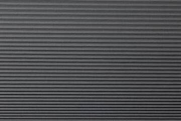 A textured black surface features evenly spaced parallel lines that create a sense of depth and...