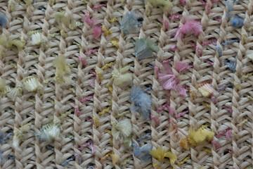 Intricate woven fabric showcases a blend of natural fibers with brightly colored threads scattered throughout. This textile reflects artistry and skill in crafting unique materials for various uses.