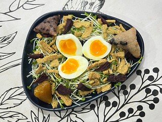 Soft-boiled egg served over sunflower sprouts, with crispy protein bites and triangle sticky rice.