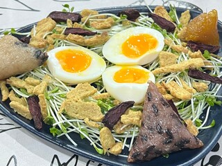 Soft-boiled egg served over sunflower sprouts, with crispy protein bites and triangle sticky rice.