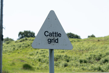 Faded road sign warning of cattle grid ahead