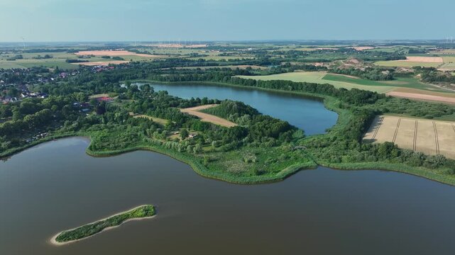 Aerial view of a tranquil lake surrounded by lush greenery and agricultural fields in Brandenburg, a scenic landscape, Brussow, Brandenburg, Germany.