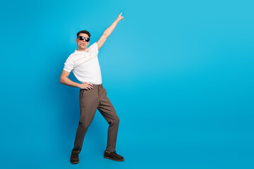 Confident man gesturing in stylish casual outfit against a bright blue background showcasing modern and trendy aesthetics