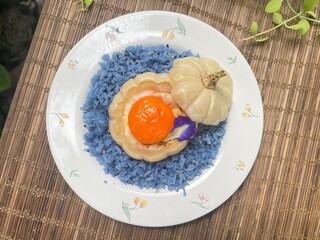 Mini pumpkin stuffed with steamed egg and egg yolk, served with blue rice.