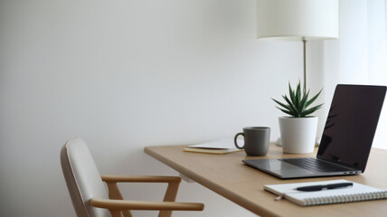 Modern minimal home office setup with a laptop notebook pen coffee mug potted plant and chair against a white wall and natural light