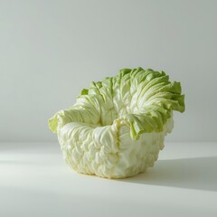 A creatively designed armchair sculpture shaped like a head of iceberg lettuce on a white background.