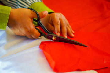 The process of cutting cloth to sew the red and white flag, Indonesia's national flag. The theme is...