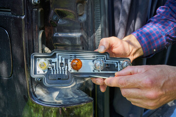 replacing a car bulb, a man holds a disassembled car headlight in his hands to replace a bulb